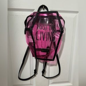 Pink translucent coffin shaped “Never Trust the Living” backpack